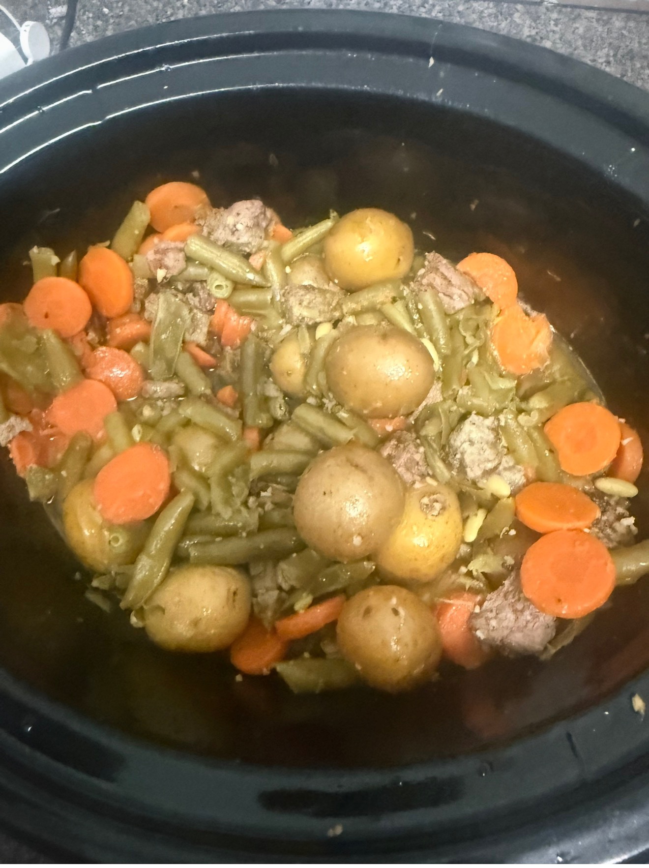 Finished slow cooker garlic butter steak bites with baby potatoes, carrots, and green beans