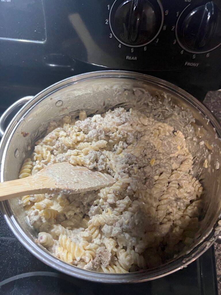 Creamy Sausage Alfredo Pasta in the pot with a wooden spoon