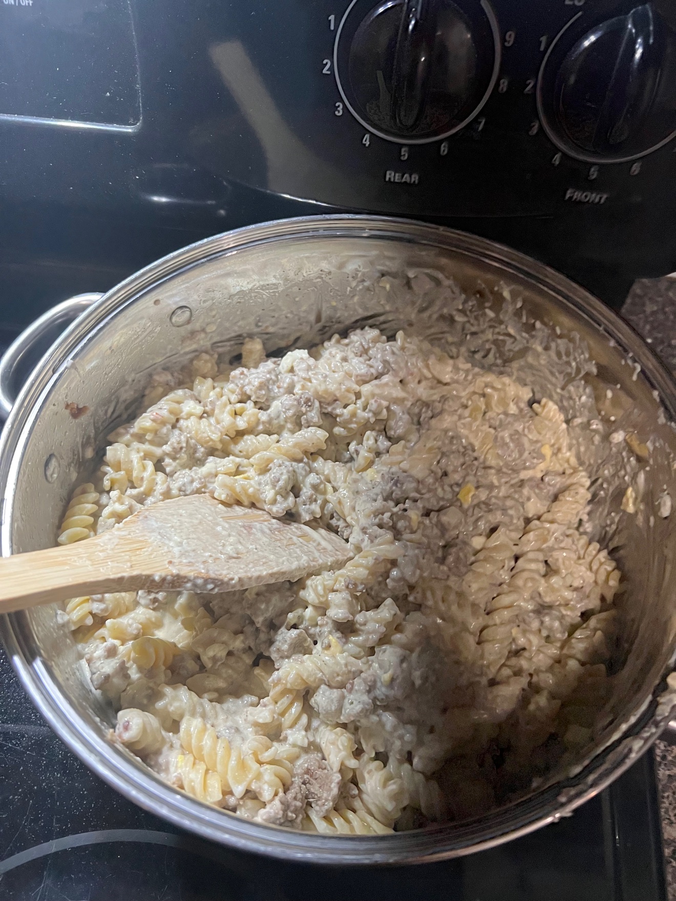 Creamy Sausage Alfredo Pasta in the pot with a wooden spoon