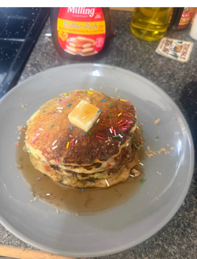 Stack of pancakes with butter, syrup, and sprinkles