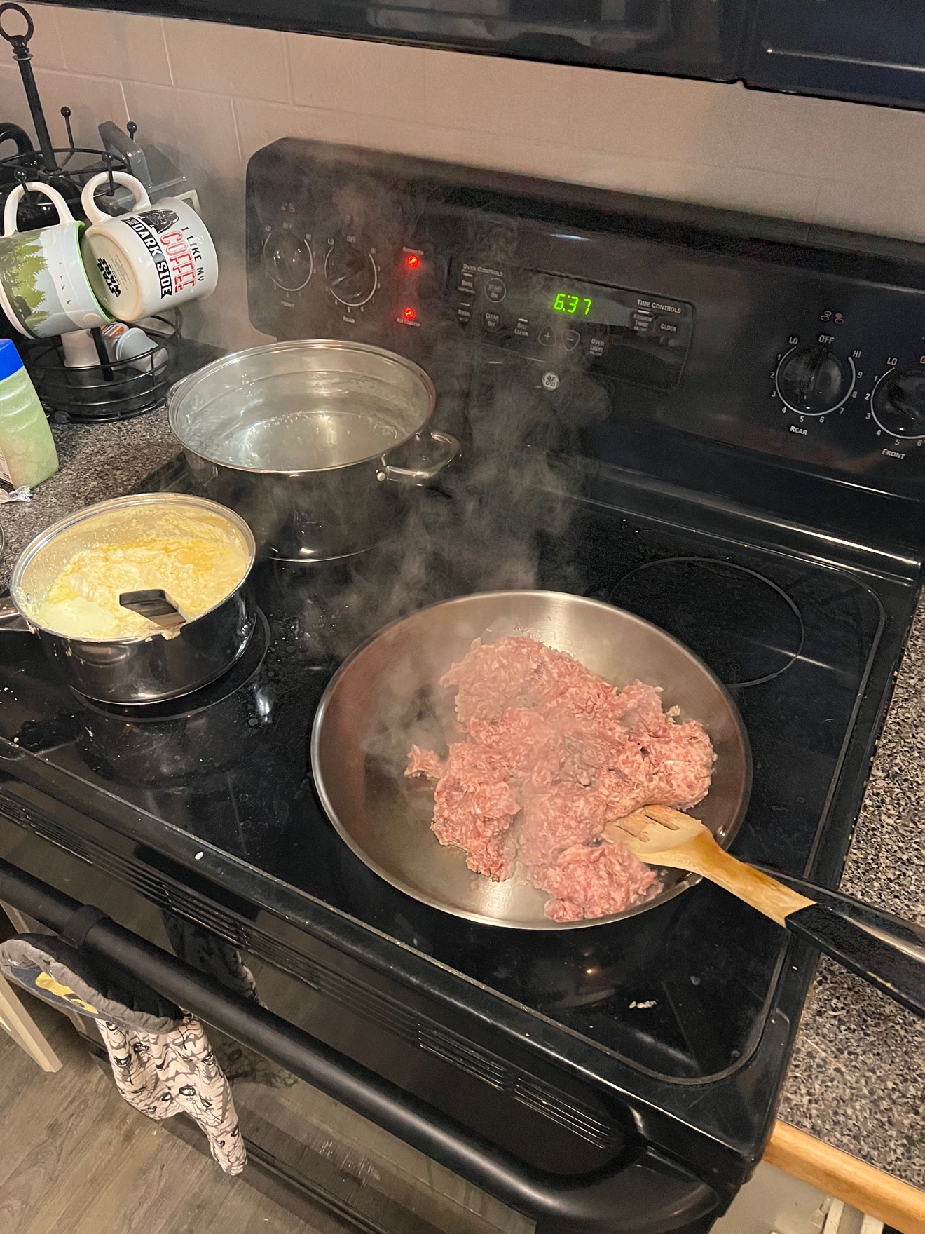 Sausage browning in the skillet, with the sauce pot and pasta pot on the stove