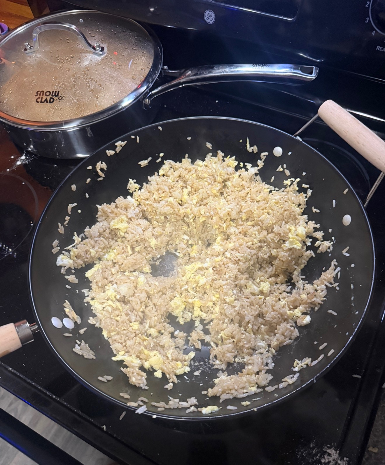 Wok on the stovetop next to a lidded pot