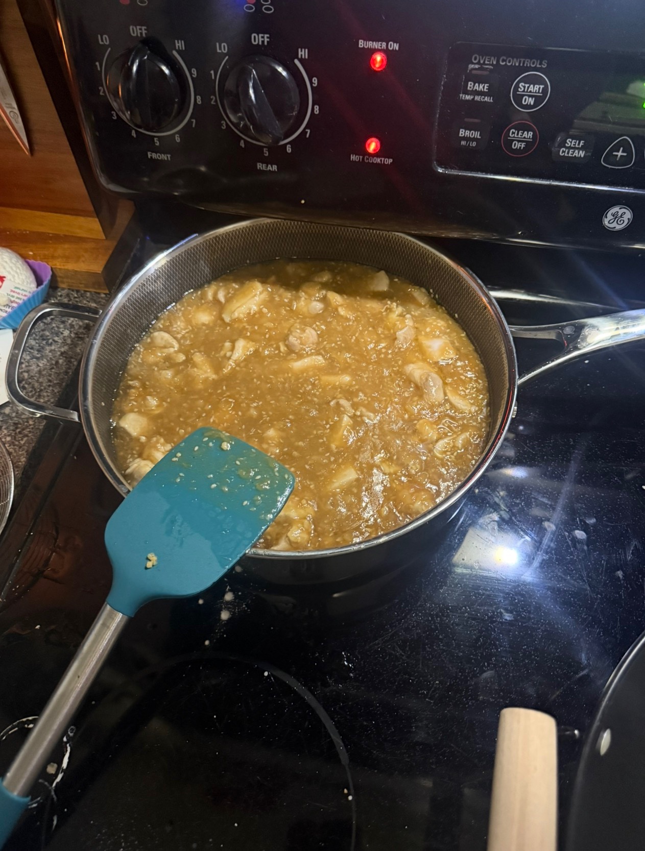 Chicken simmering in sauce on the stove